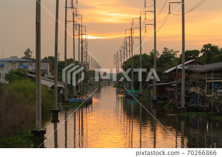 Utility poles tower and cable wires and Chao Phraya River with reflection of lake at sunset in Bangkok, Thailand in energy electric technology and industry concept. Utility poles tower and cable wires and Chao Phraya River with reflection of lake at sunset in Bangkok, Thailand in energy electric technology and industry concept. 70266866