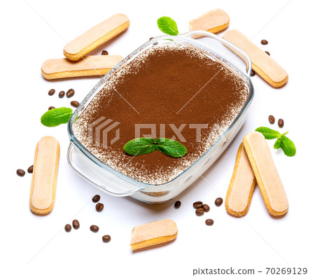 Traditional Italian Tiramisu dessert in glass baking dish and savoiardi cookies isolated on white Traditional Italian Tiramisu dessert in glass baking dish and savoiardi cookies isolated on white 70269129