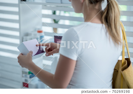 Woman in white tshirt choosing medicines in the drug store Woman in white tshirt choosing medicines in the drug store 70269198