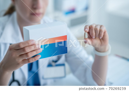 Woman in a lab coat presenting new medicine 70269239