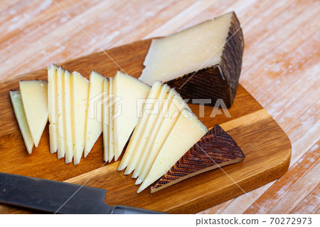 Sliced wedge of aged sheep cheese on wooden board 70272973