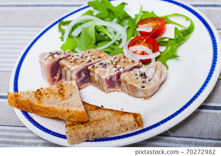 Tasty lightly fried tuna, served at plate with bread and greens Tasty lightly fried tuna, served at plate with bread and greens 70272982