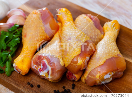 Raw chicken drumsticks and condiments on wooden table Raw chicken drumsticks and condiments on wooden table 70273044