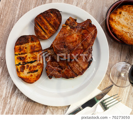 Baked pork bone-in sirloin chops with grilled potatoes Baked pork bone-in sirloin chops with grilled potatoes 70273050