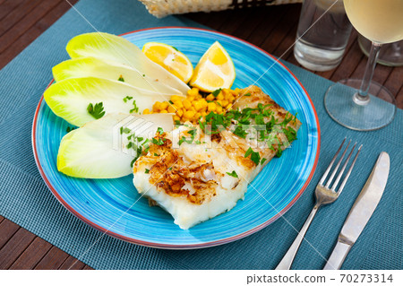 Delicious fried cod fillet with endive, corn, and greens Delicious fried cod fillet with endive, corn, and greens 70273314