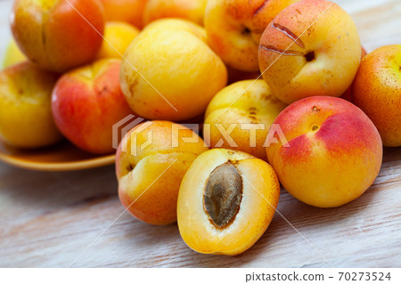 Fresh apricots whole and halves on wooden table Fresh apricots whole and halves on wooden table 70273524