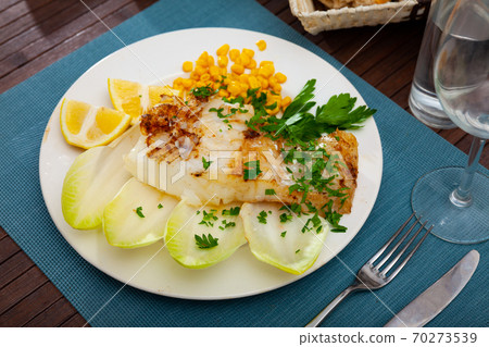 Fried rockling fillet with corn, lemon and greens 70273539