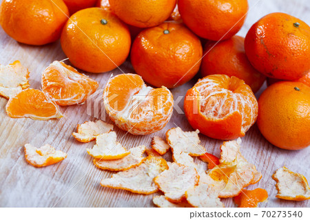 Ripe peeled tangerines on wooden table in kitchen 70273540