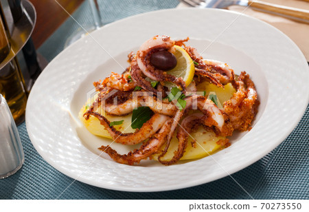 Delicious cooked squid or octopus tentacles with lemon and parsley on a plate 70273550