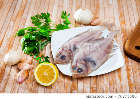 Two raw megrims on wooden table with condiments Two raw megrims on wooden table with condiments 70273596