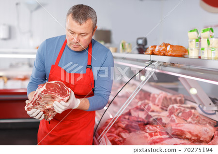 Positive man seller demonstration meat in shop Positive man seller demonstration meat in shop 70275194