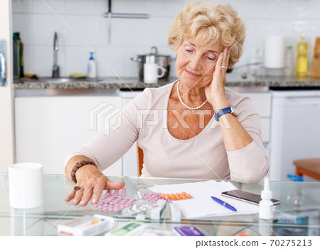 Confused woman among a lot of medicines 70275213