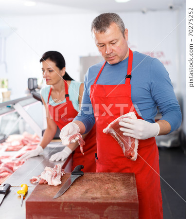Sellers working in shop, man demonstrating meat Sellers working in shop, man demonstrating meat 70275252