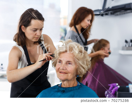 Hairdresser making hairstyle for elderly female Hairdresser making hairstyle for elderly female 70275286