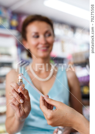 Young girl and mother smelling perfume testers in cosmetic store 70275508