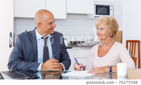 Senior woman signs document about purchase Senior woman signs document about purchase 70275598
