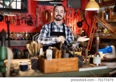 Male worker demonstrating workplace and tools in leather Male worker demonstrating workplace and tools in leather 70275879
