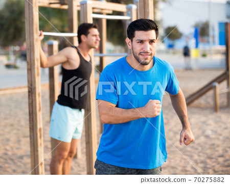 Portrait of adult man who is jogging when his friend is pulling-up 70275882