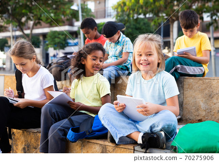 Preteen classmates preparing schoolwork outside school Preteen classmates preparing schoolwork outside school 70275906