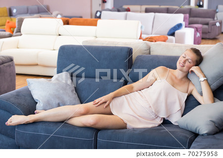 Cheerful woman with pillow on the sofa in furniture shop Cheerful woman with pillow on the sofa in furniture shop 70275958