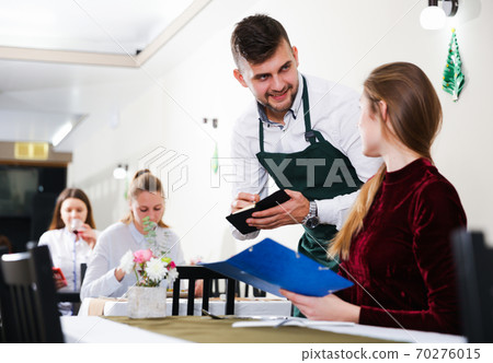Cheerful woman is giving order to male waiter in luxury restaurante Cheerful woman is giving order to male waiter in luxury restaurante 70276015