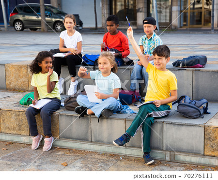 Schoolchildren with hands raised during lesson outside school Schoolchildren with hands raised during lesson outside school 70276111