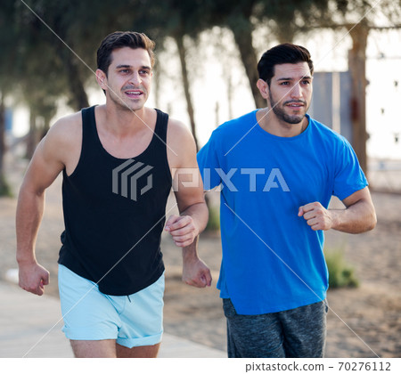 Smiling sportsmen are joggning in time warm-up Smiling sportsmen are joggning in time warm-up 70276112