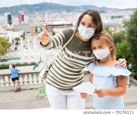 Young woman in medical mask pointing to sightseeing with daughter Young woman in medical mask pointing to sightseeing with daughter 70276113