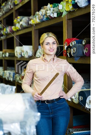 Saleswoman offering cloth in textile shop 70276149