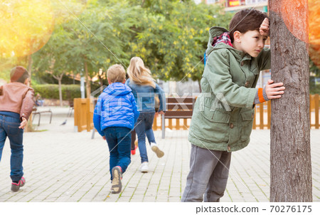 Kids playing hide and seek on the street Kids playing hide and seek on the street 70276175