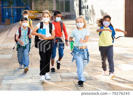 Tweenagers in medical masks walking outside school building Tweenagers in medical masks walking outside school building 70276243
