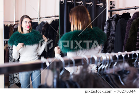 Girl deciding on the choice of fur neckpiece 70276344