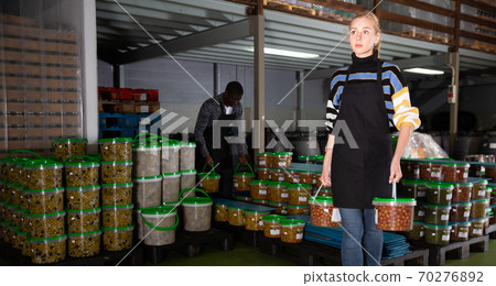 Workers store plastic containers with ripe olives in factory 70276892