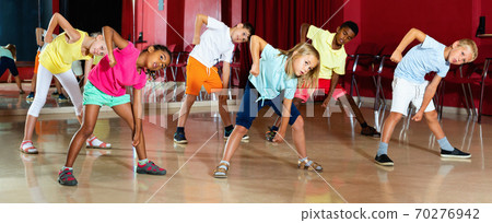 Positive children studying modern style dance in class indoors Positive children studying modern style dance in class indoors 70276942