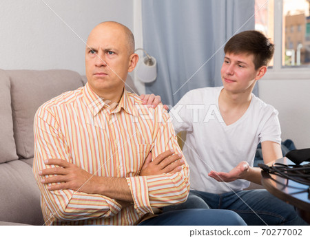 Guy trying to talk with his offended father Guy trying to talk with his offended father 70277002