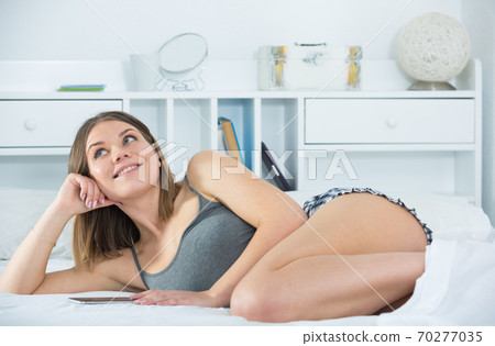 Portrait of young sexy woman lying with smartphone in bed 70277035