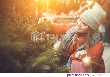 Young woman selecting Christmas tree Young woman selecting Christmas tree 70277156