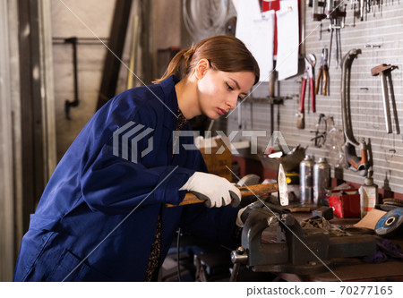 Young woman handles part on bench vise Young woman handles part on bench vise 70277165