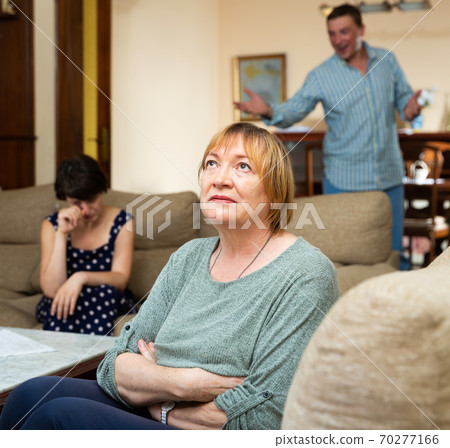 Woman sitting during family conflict, woman on background crying Woman sitting during family conflict, woman on background crying 70277166