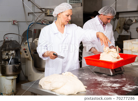 Female baker portioning dough 70277286