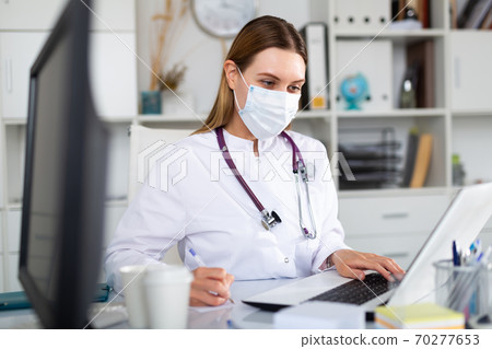 Female doctor in lab coat and protective medical masks 70277653