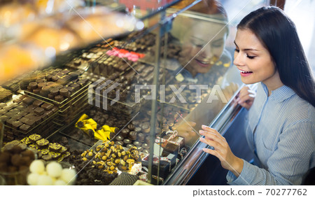 brunette girl buying dark and white chocolate with fillings brunette girl buying dark and white chocolate with fillings 70277762