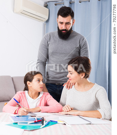 Parents helping daughter with homework Parents helping daughter with homework 70277798