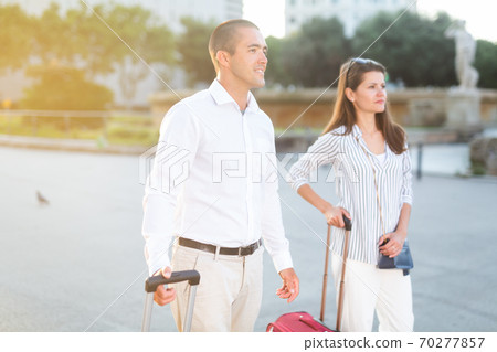 Tourist couple walking around city with suitcases 70277857