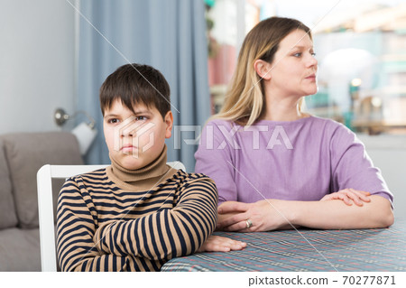 Offended son sitting at tablr after quarrel with mother at home 70277871