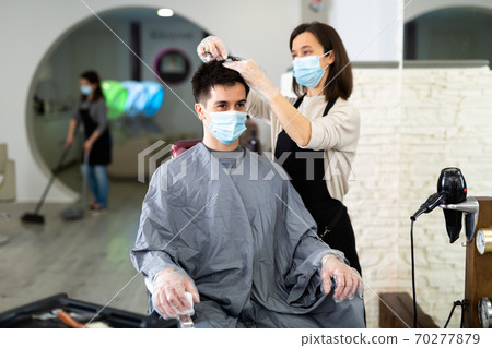 Client in mask during hair cut by professional hairdresser in mask Client in mask during hair cut by professional hairdresser in mask 70277879