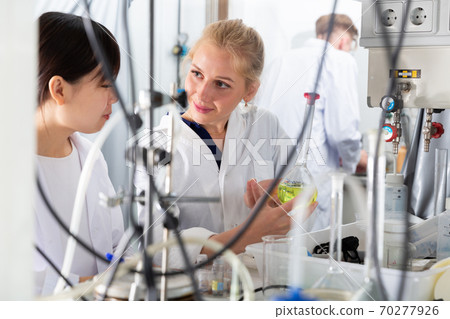 Woman lab technician with female assistant working with reagents Woman lab technician with female assistant working with reagents 70277926