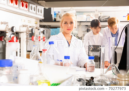 Portrait of young female scientist near laboratory equipment at biochemical lab Portrait of young female scientist near laboratory equipment at biochemical lab 70277973
