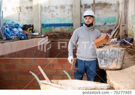 Bricklayer installing brick wall 70277985