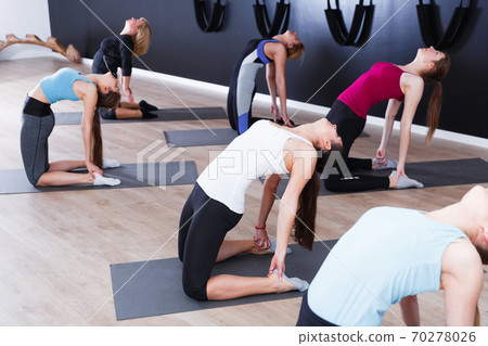 Women exercising yoga poses in fitness center 70278026